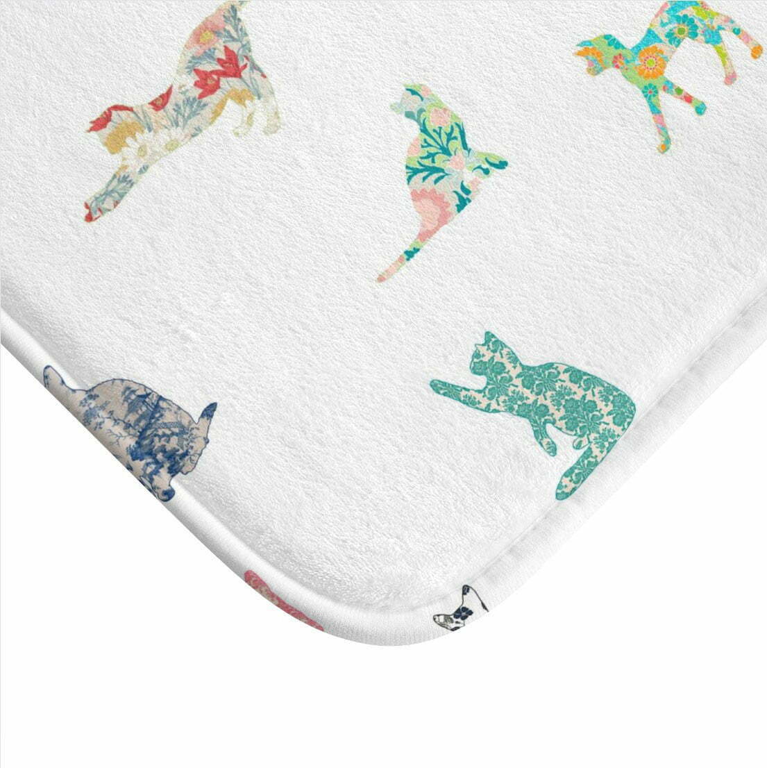Close-up of a patchwork cat design on a white memory foam bath mat.
