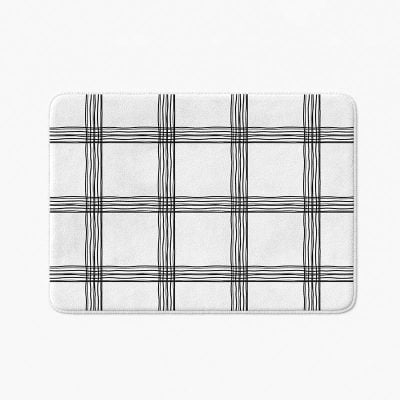Black and white checked bath mat with artist-designed geometric pattern.