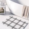 Black and white checked bath mat with artist-designed geometric pattern.
