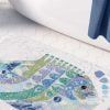 Patterned bath mat featuring abstract big blue raku fish artwork.