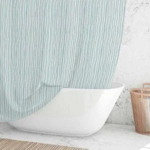 Coastal blue striped shower curtain hanging over a white bathtub in a bright beach-style bathroom