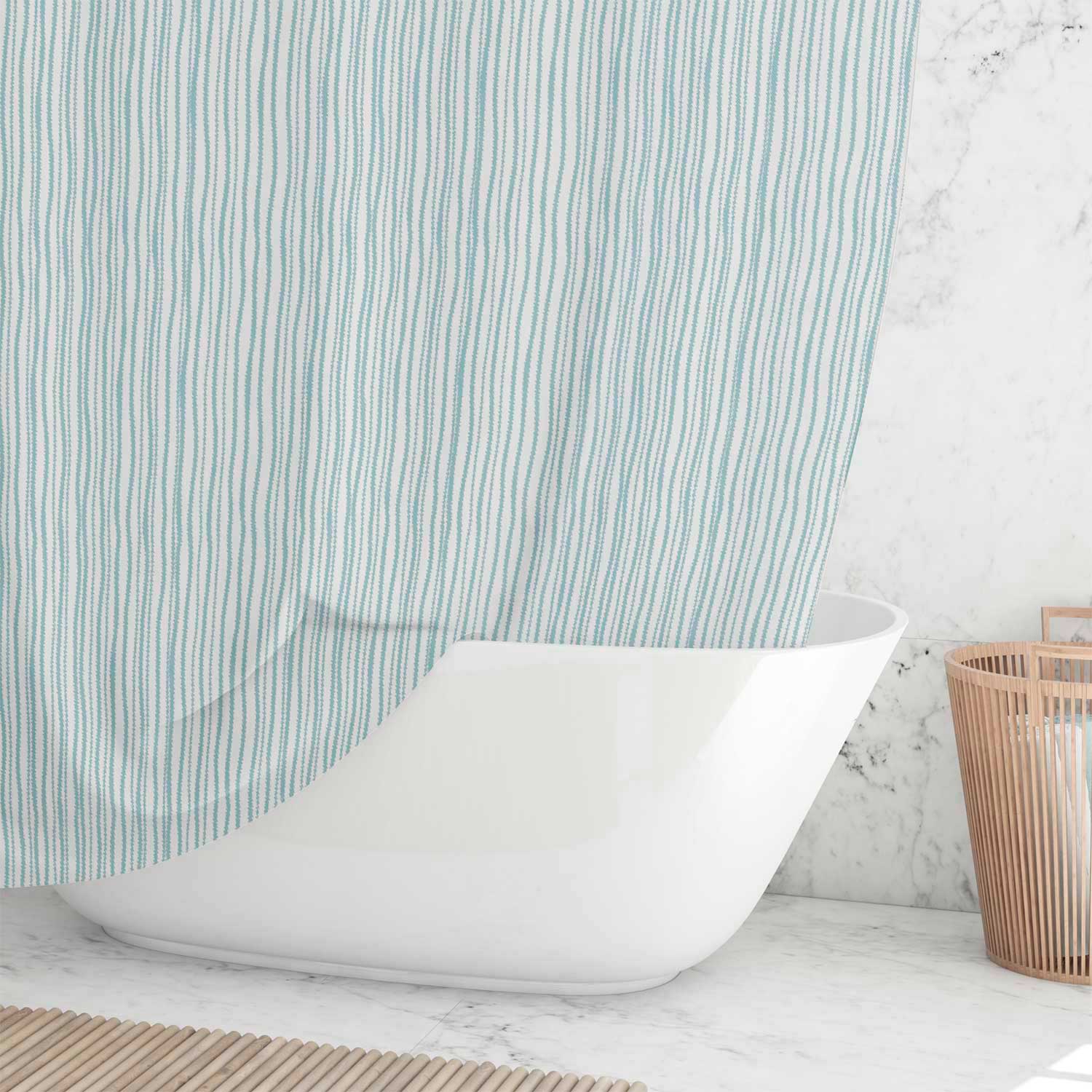 Coastal blue striped shower curtain hanging over a white bathtub in a bright beach-style bathroom