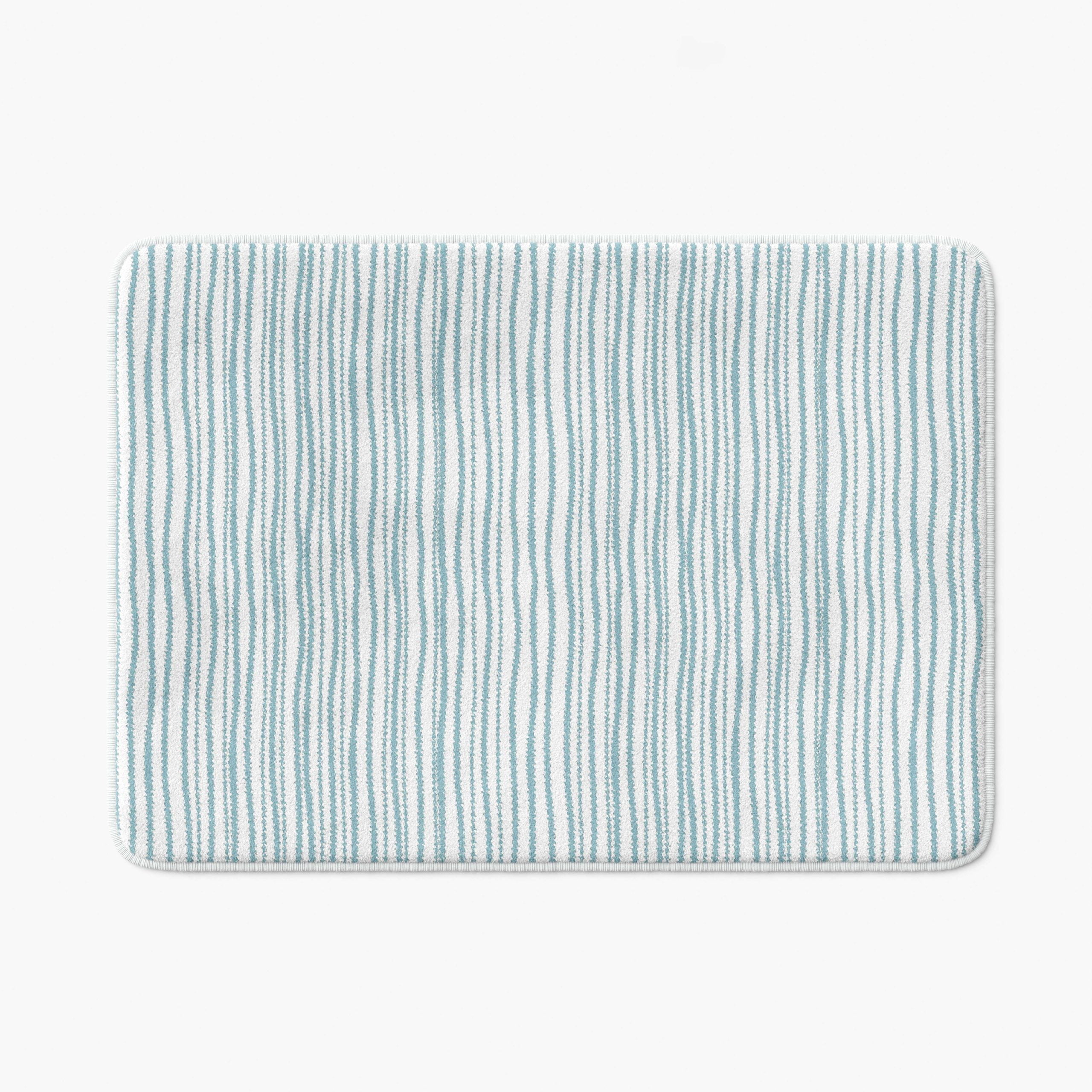A coastal blue striped bath mat perfect for a small bathroom, master, or guest bathroom. Mold and mildew resistant, quick-drying, non-slip plush microfiber, washable.